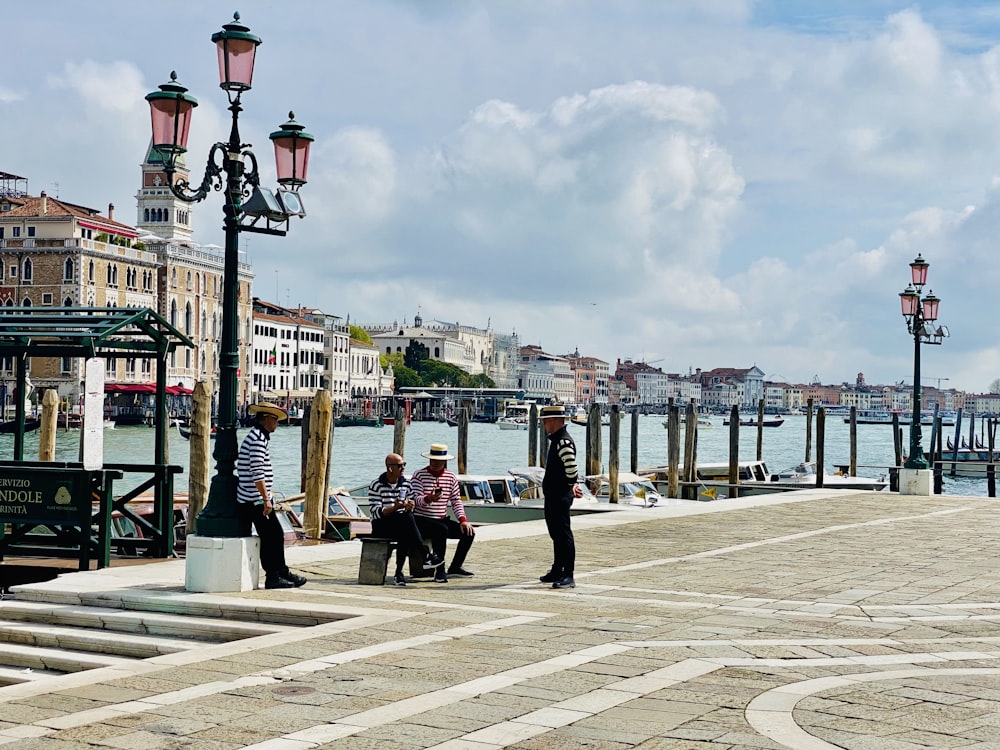 a group of people sitting on a bench by a body of water