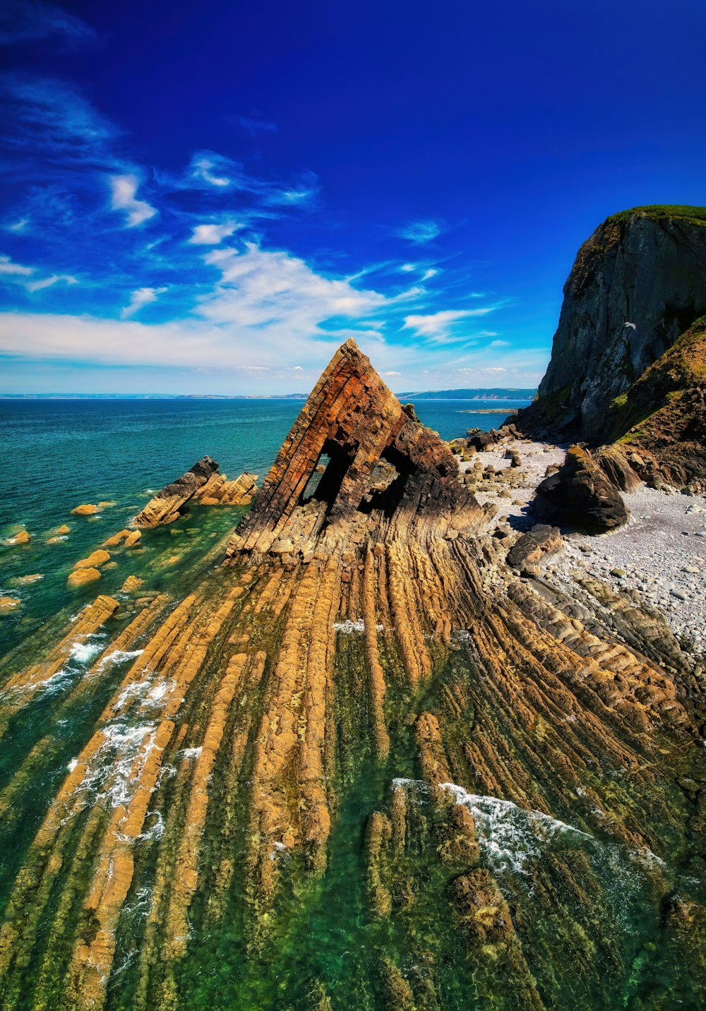 a rocky cliff with a body of water in the background