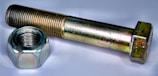 A metallic bolt and nut are placed on a white surface. The bolt has a hexagonal head and is positioned parallel to the nut, which is similarly hexagonal and threaded. Both objects have a shiny metallic surface with slight colorful reflections due to the lighting.