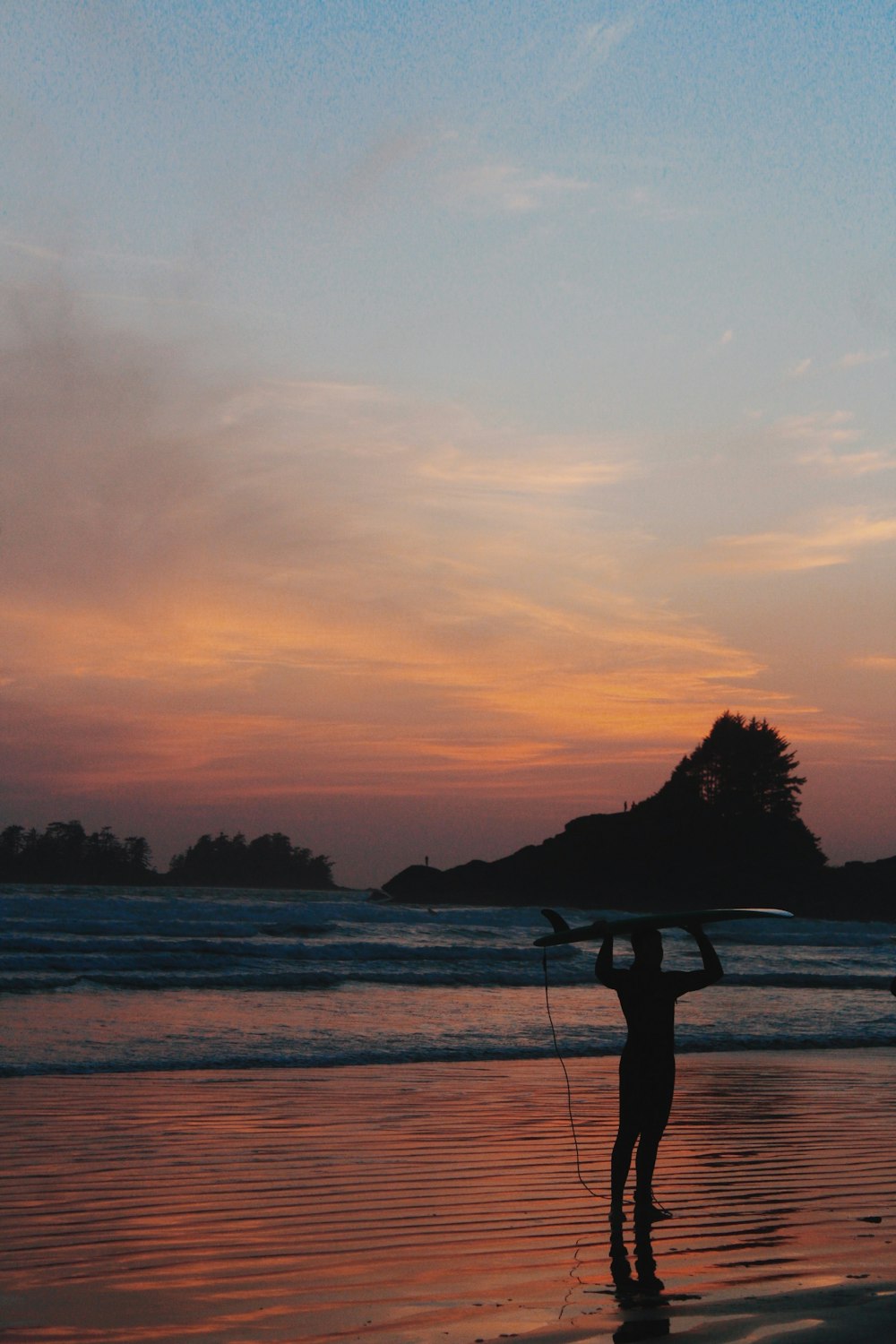 a person holding a surfboard on a beach