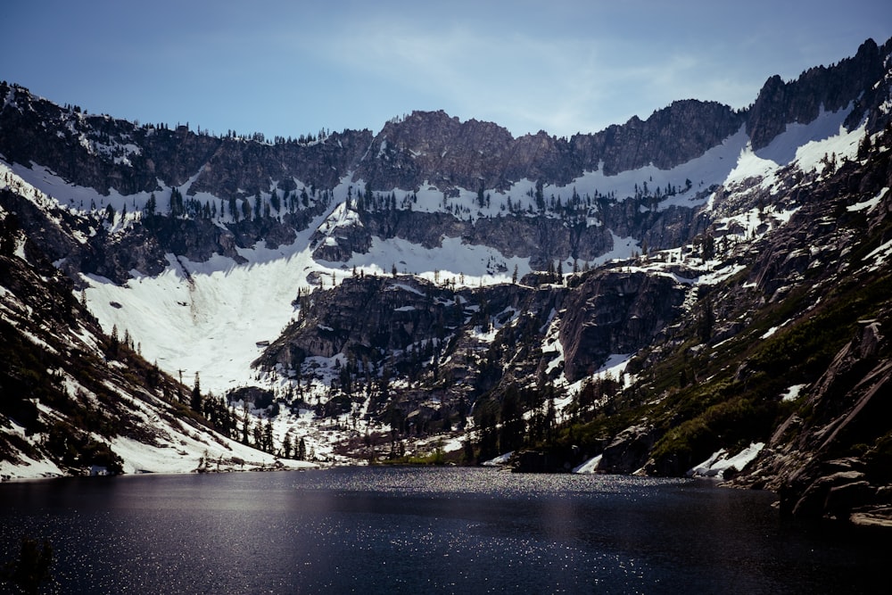 a body of water with snow covered mountains in the background