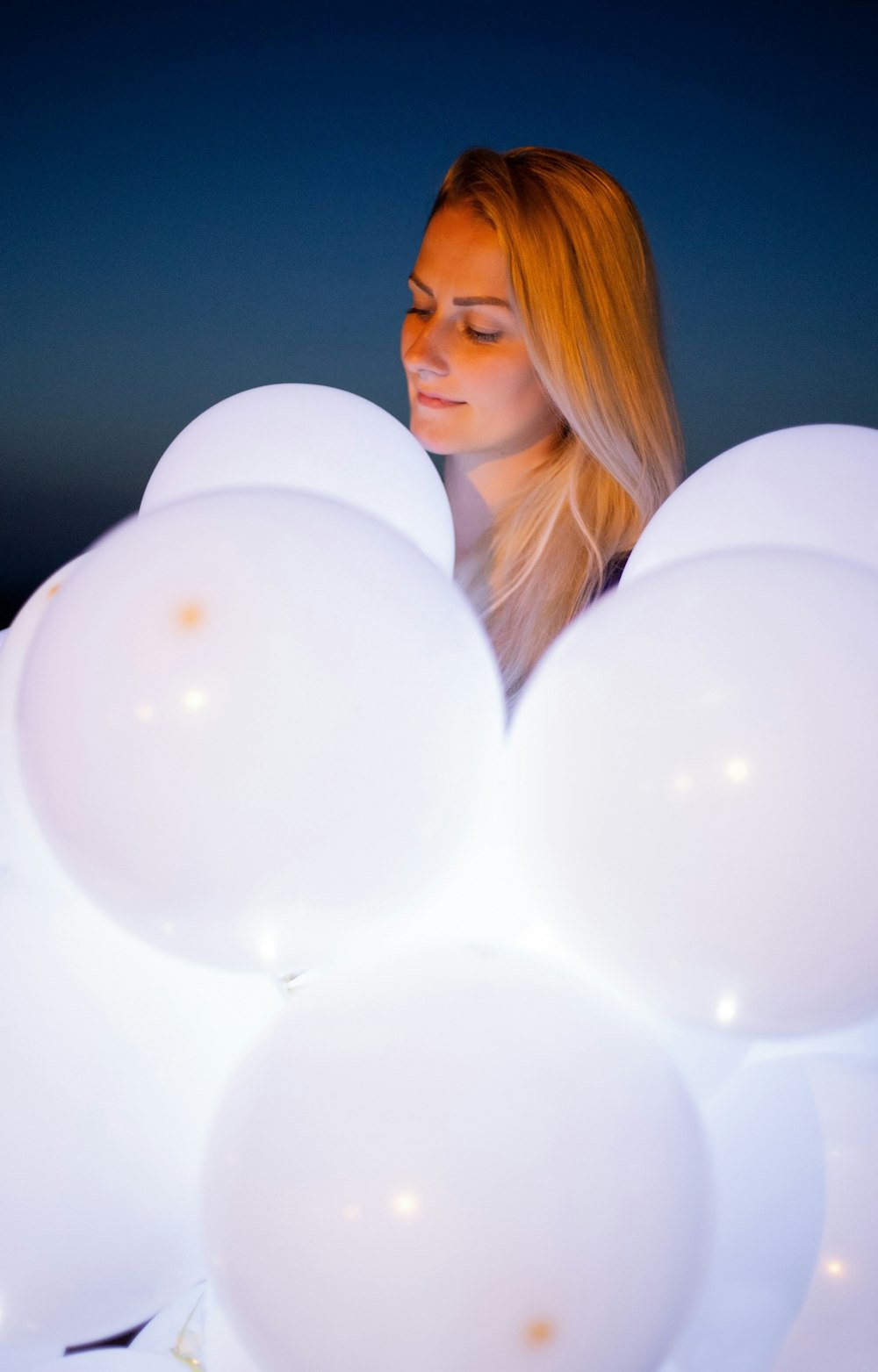 a woman looking at a white balloon