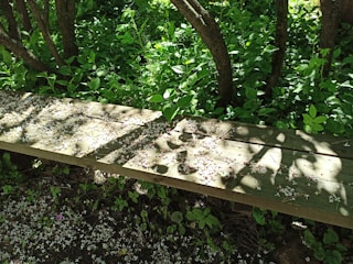 A rustic wooden bench crafted by hand, surrounded by blooming garden flowers.