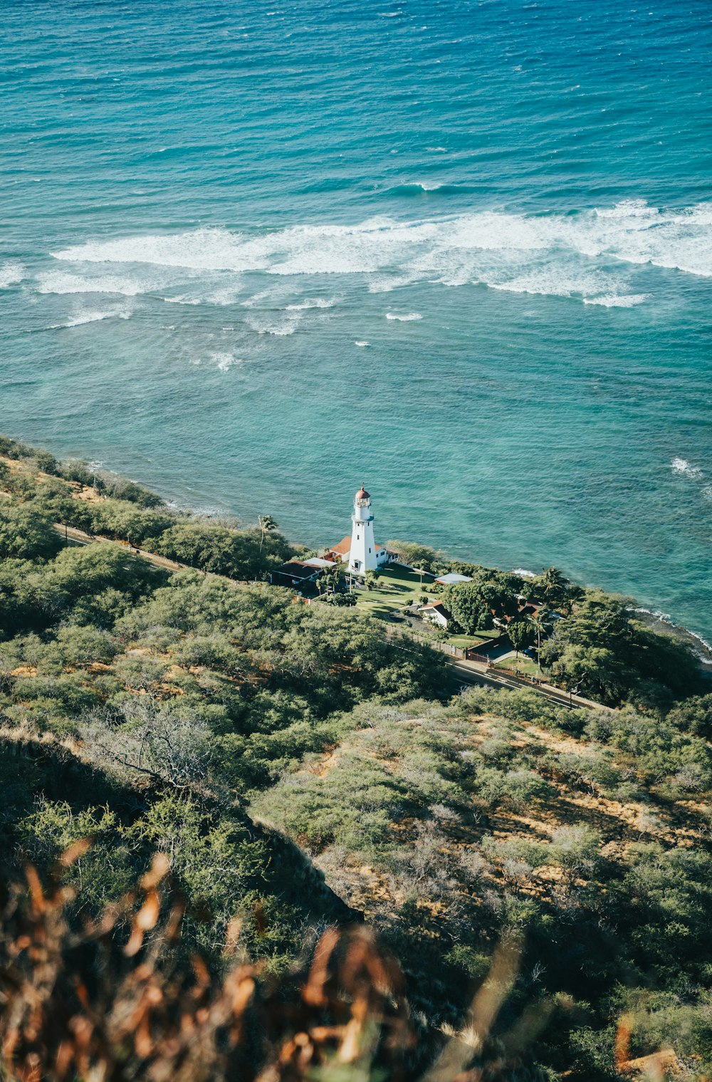 a statue on a hill by the ocean with Diamond Head Lighthouse in the background