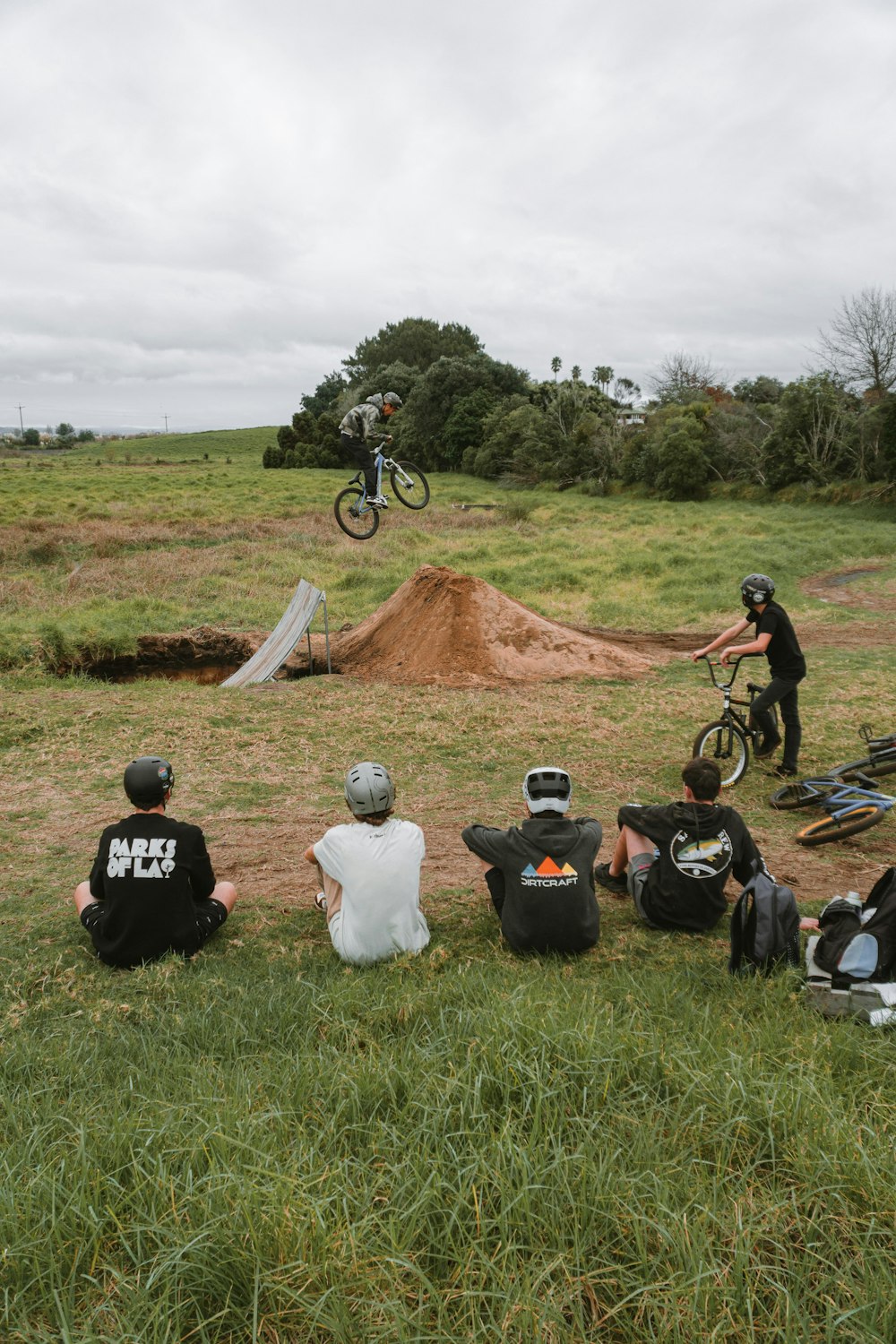 a group of people sitting on the ground with bikes and a person on a bike