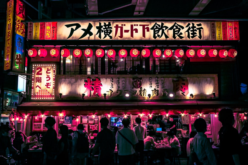 a group of people in front of a building with neon signs