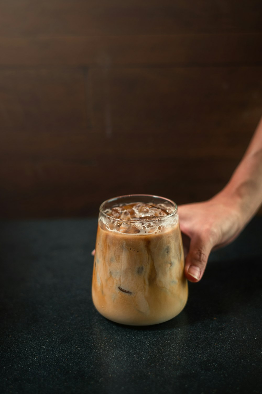 a hand holding a glass of liquid