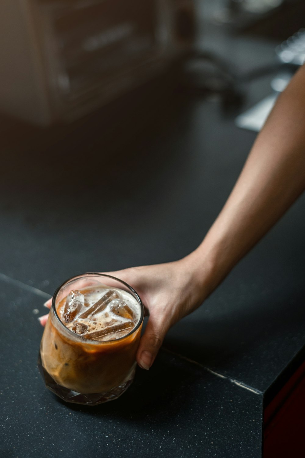 a hand holding a glass of liquid