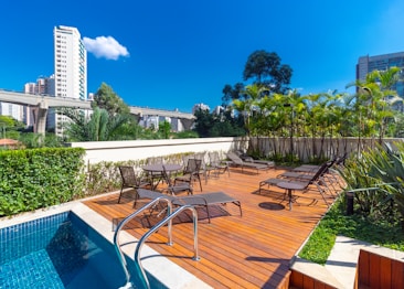 a pool with chairs and tables by it and buildings in the background