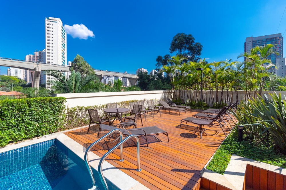 a pool with chairs and tables by it and buildings in the background