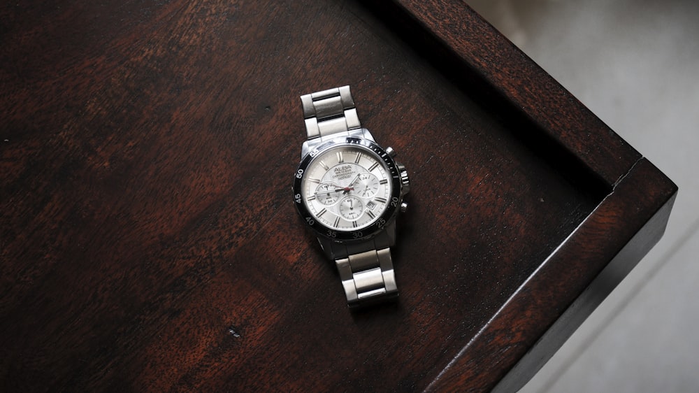 a silver watch on a wooden surface