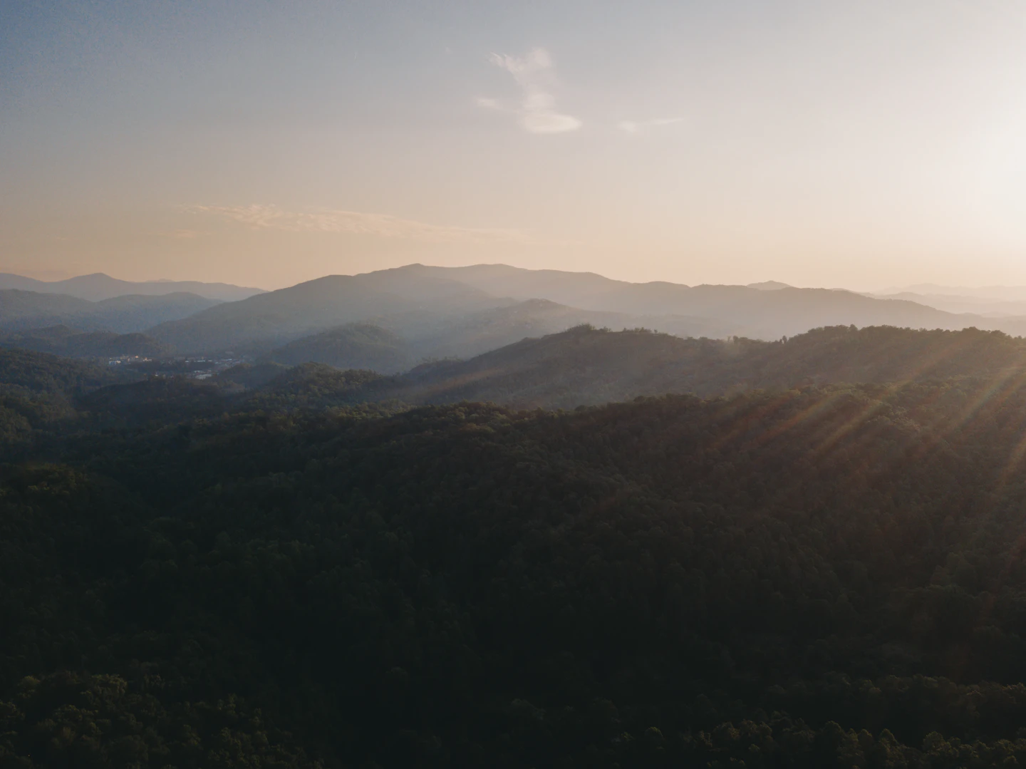 Sun rays breaking over layered ridges of the Great Smoky Mountains at sunset.