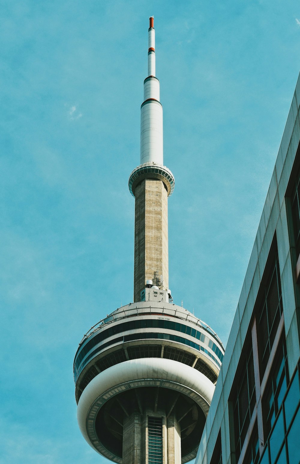 a tall tower with a cylindrical top with CN Tower in the background