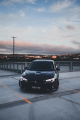 A sleek black stretch limousine parked against a city skyline at dusk.