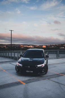 A sleek black stretch limousine parked against a city skyline at dusk.