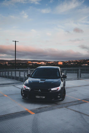 A futuristic car parked against a city skyline at dusk.