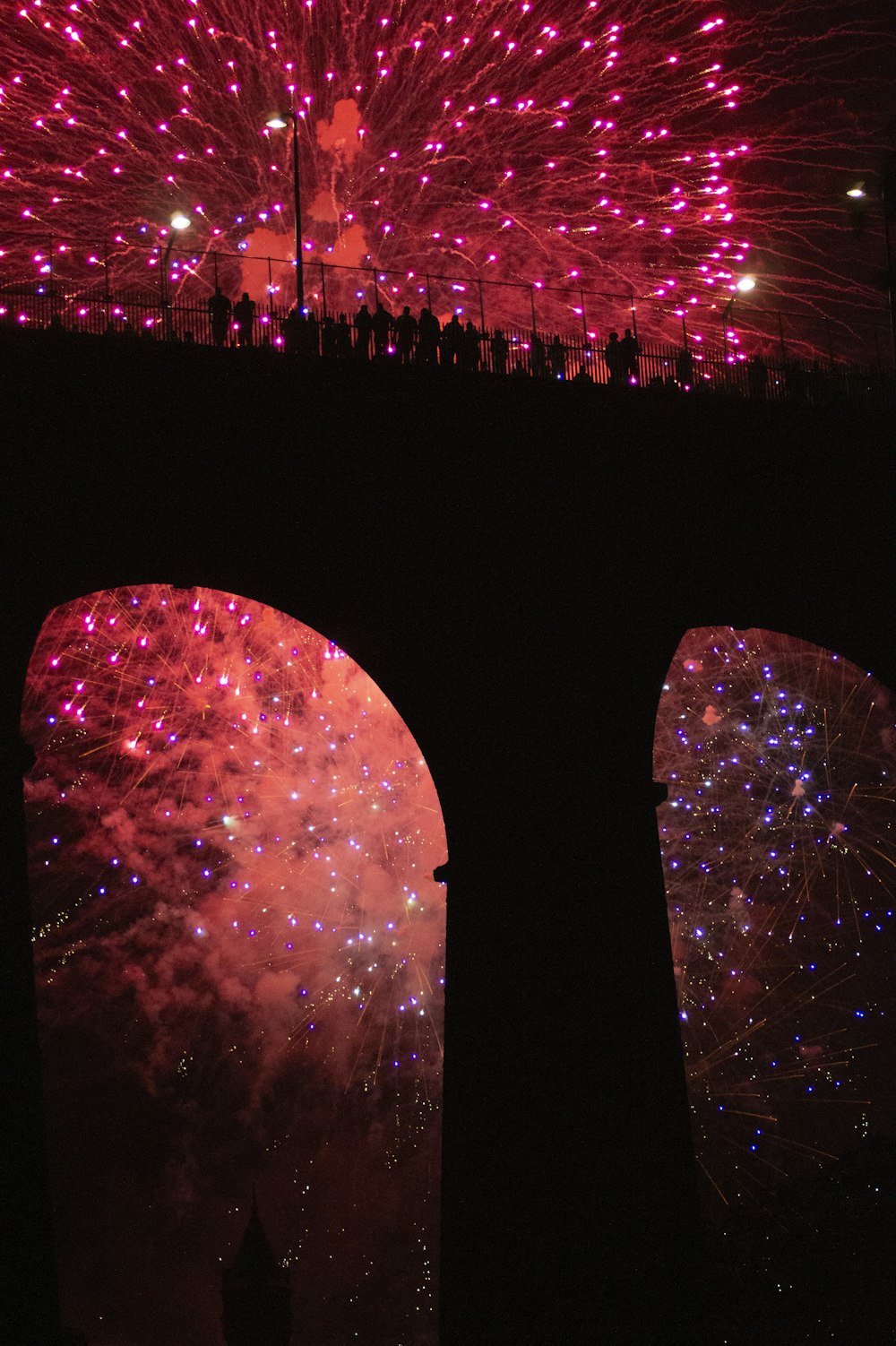 a group of people standing in front of a large firework display