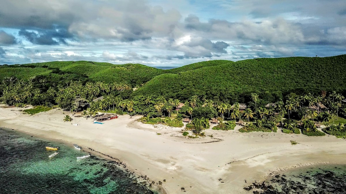 A tropical beach with palm trees and hills in Fiji