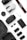 A collection of photography and drone equipment neatly arranged on a white surface. There is a camera lens, a drone, a camera strap with the Canon logo, several batteries, a battery charger, and memory cards. The black and white color scheme gives it a professional and sleek appearance.