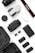 A collection of photography and drone equipment neatly arranged on a white surface. There is a camera lens, a drone, a camera strap with the Canon logo, several batteries, a battery charger, and memory cards. The black and white color scheme gives it a professional and sleek appearance.