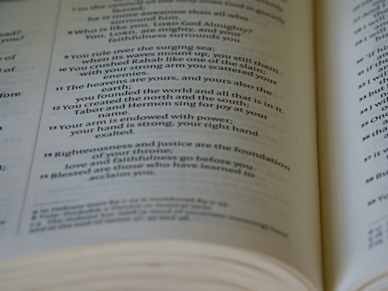 An open book displaying text on its pages, focused on a passage with a verse number. The text is printed in a serif font, with a soft yellow hue to the paper.