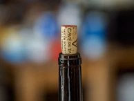 Close-up of a personalized wine label being applied to a freshly bottled wine.