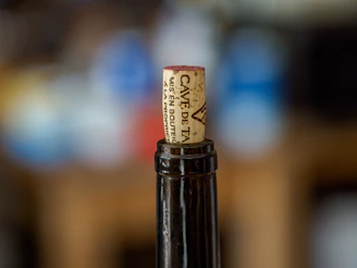 Close-up of a personalized wine label being applied to a freshly bottled wine.
