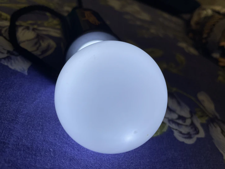 Close-up of a rugged Olight flashlight glowing softly on a wooden surface.