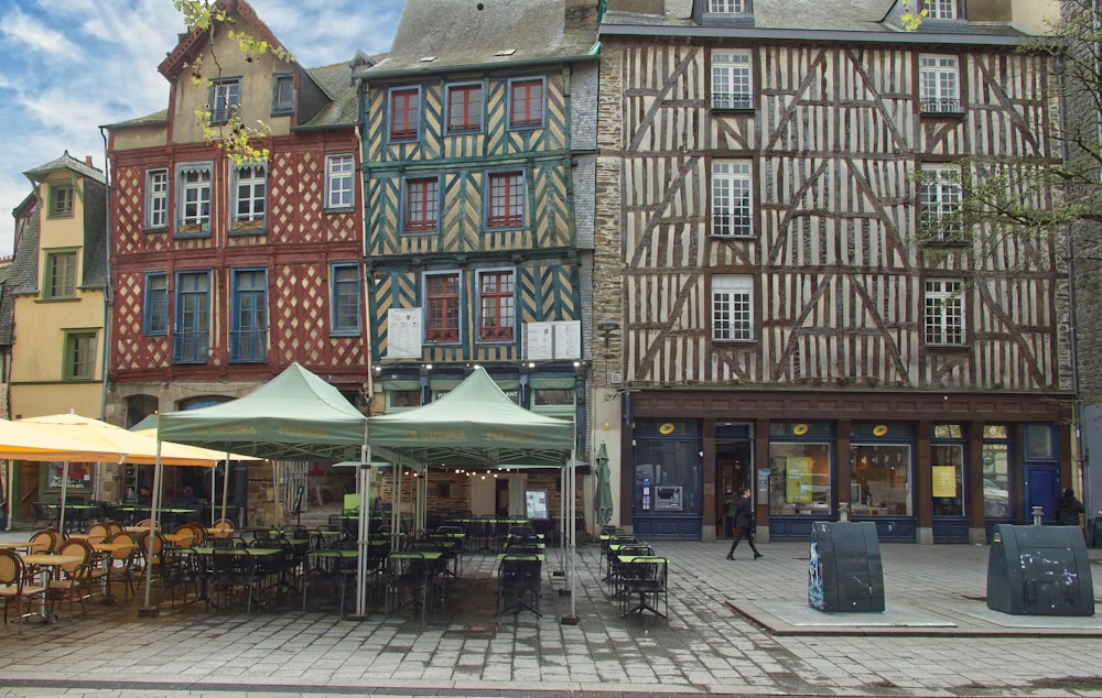 a group of buildings with tables and chairs outside