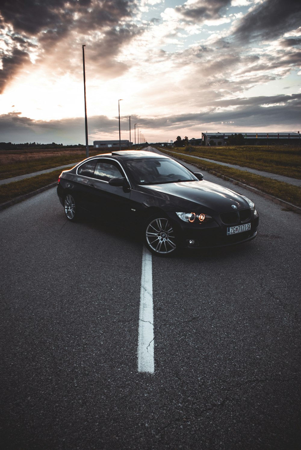 a black sports car parked on a road with a sunset in the background