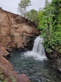 A secret waterfall cascading into a crystal-clear pool surrounded by rocks.