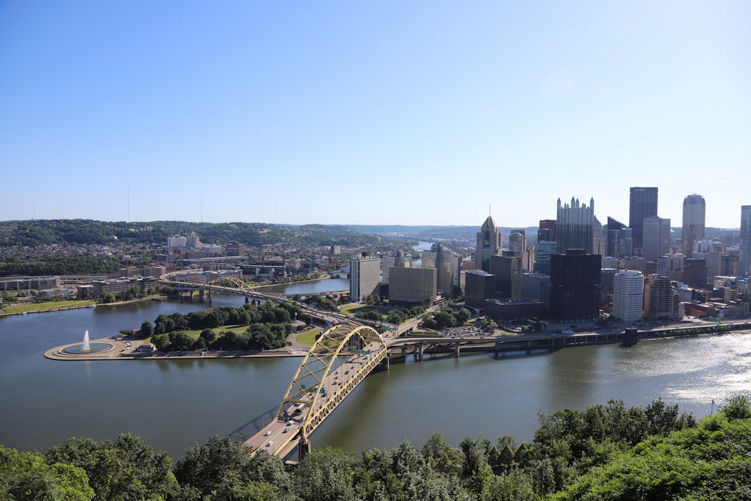 a bridge over a river with a city in the background, Pittsburgh skyline and fountain