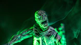 An eerie cryptid silhouette lurking near a fog-covered lake, bathed in neon green light.