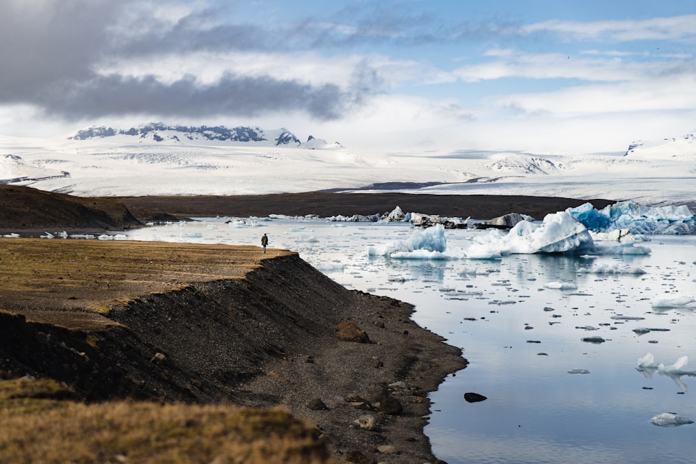 a body of water with ice and snow on the side