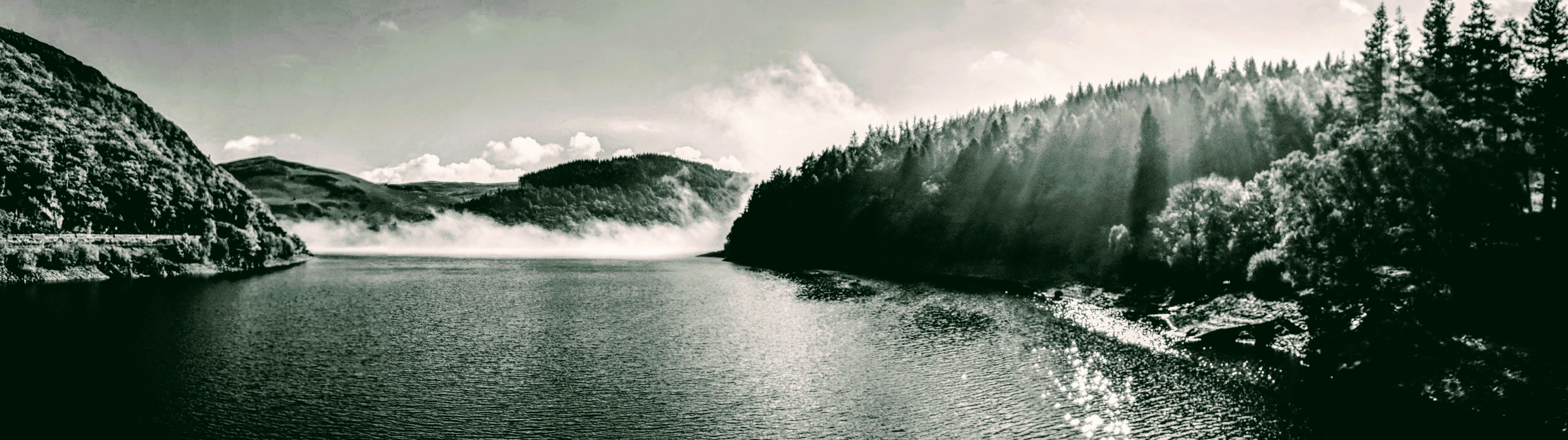a body of water with trees and mountains in the background