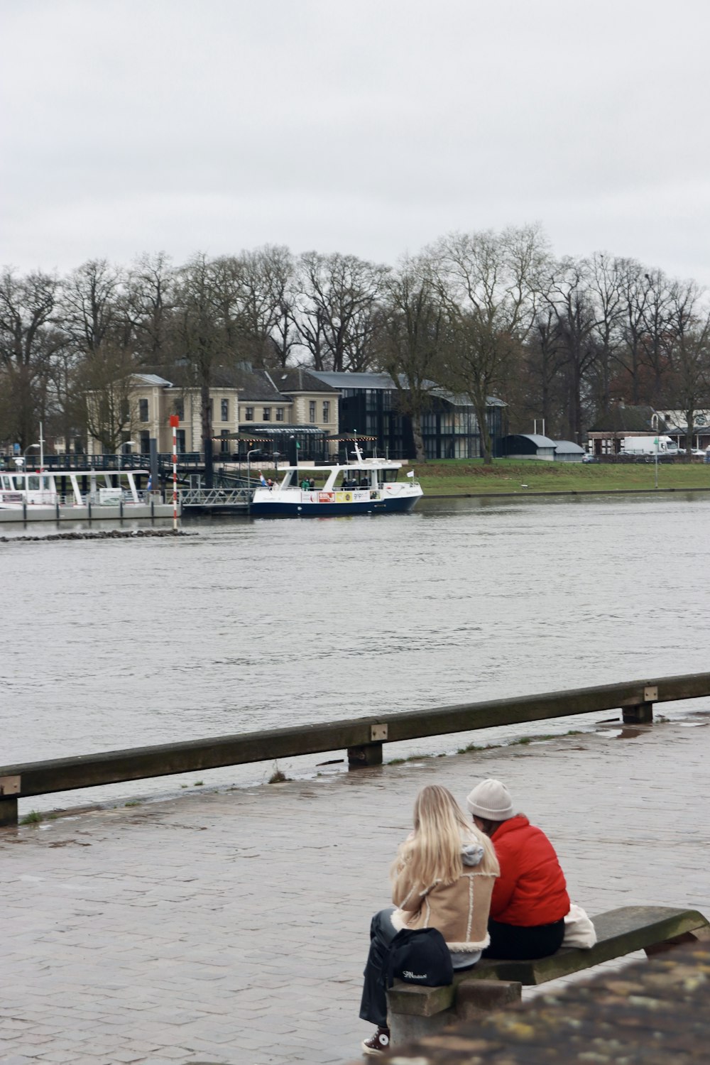 a couple of people sitting on a bench by a body of water