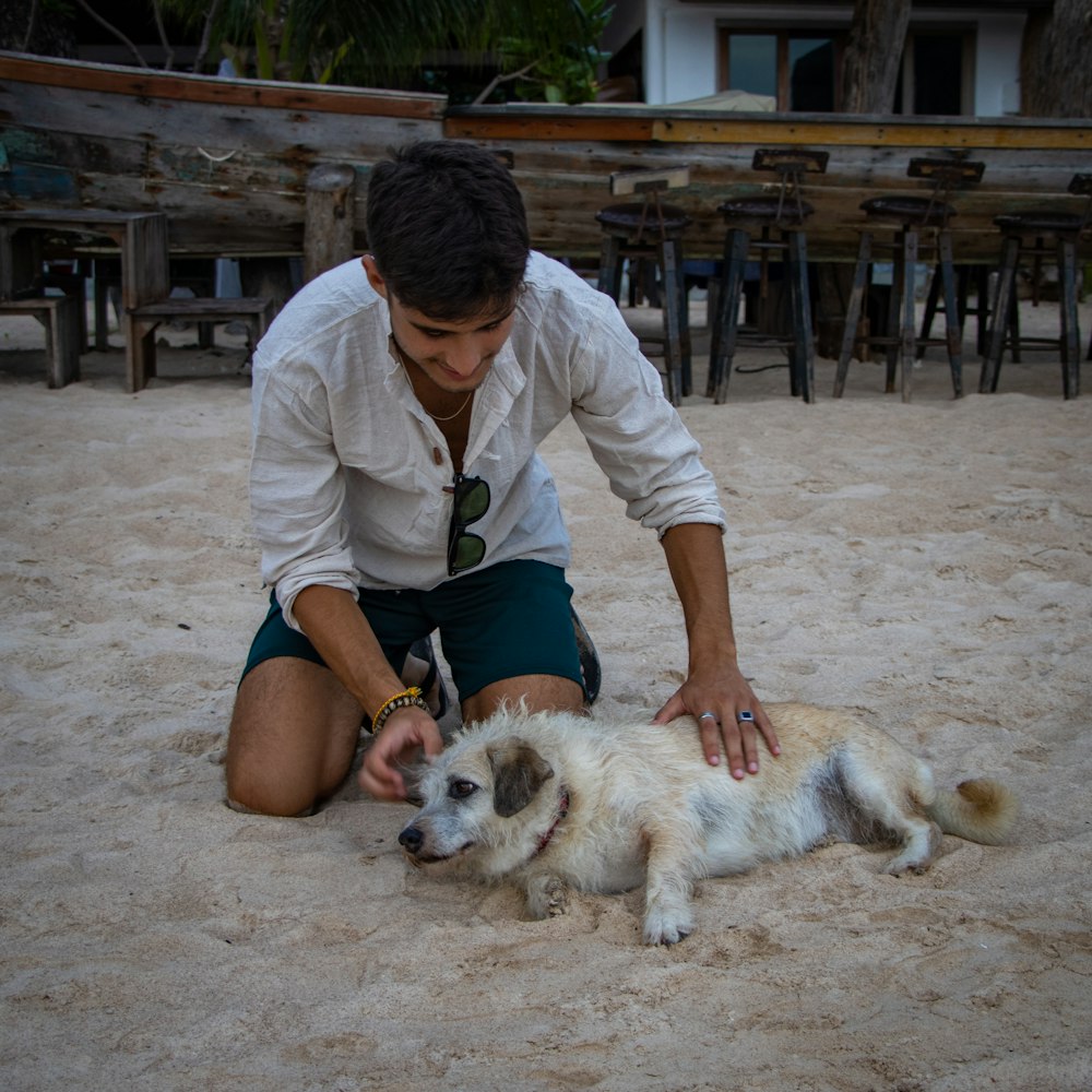 a person kneeling down next to a dog lying on the ground