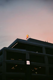 A skilled technician installing a sleek illuminated sign on a modern building facade during sunset.