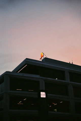 A skilled technician installing a sleek illuminated sign on a modern building facade during sunset.