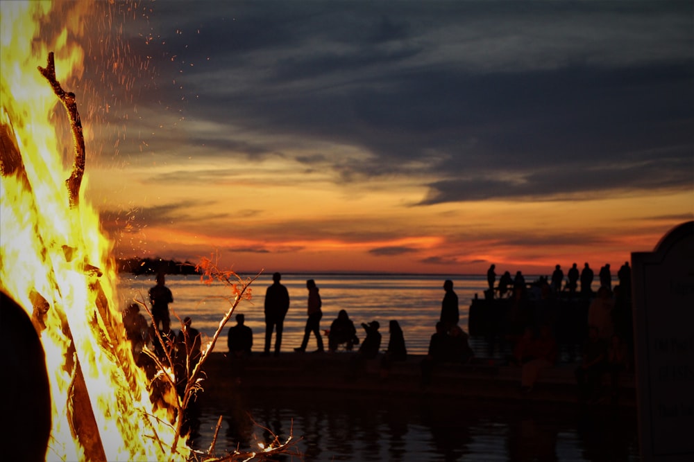 a group of people standing on a dock at sunset