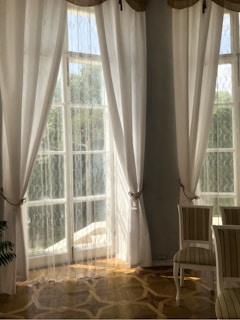 A spacious living room with large windows and elegant decor.