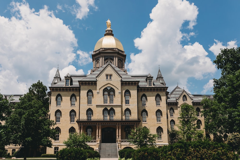 a large building with a dome and trees in front of it