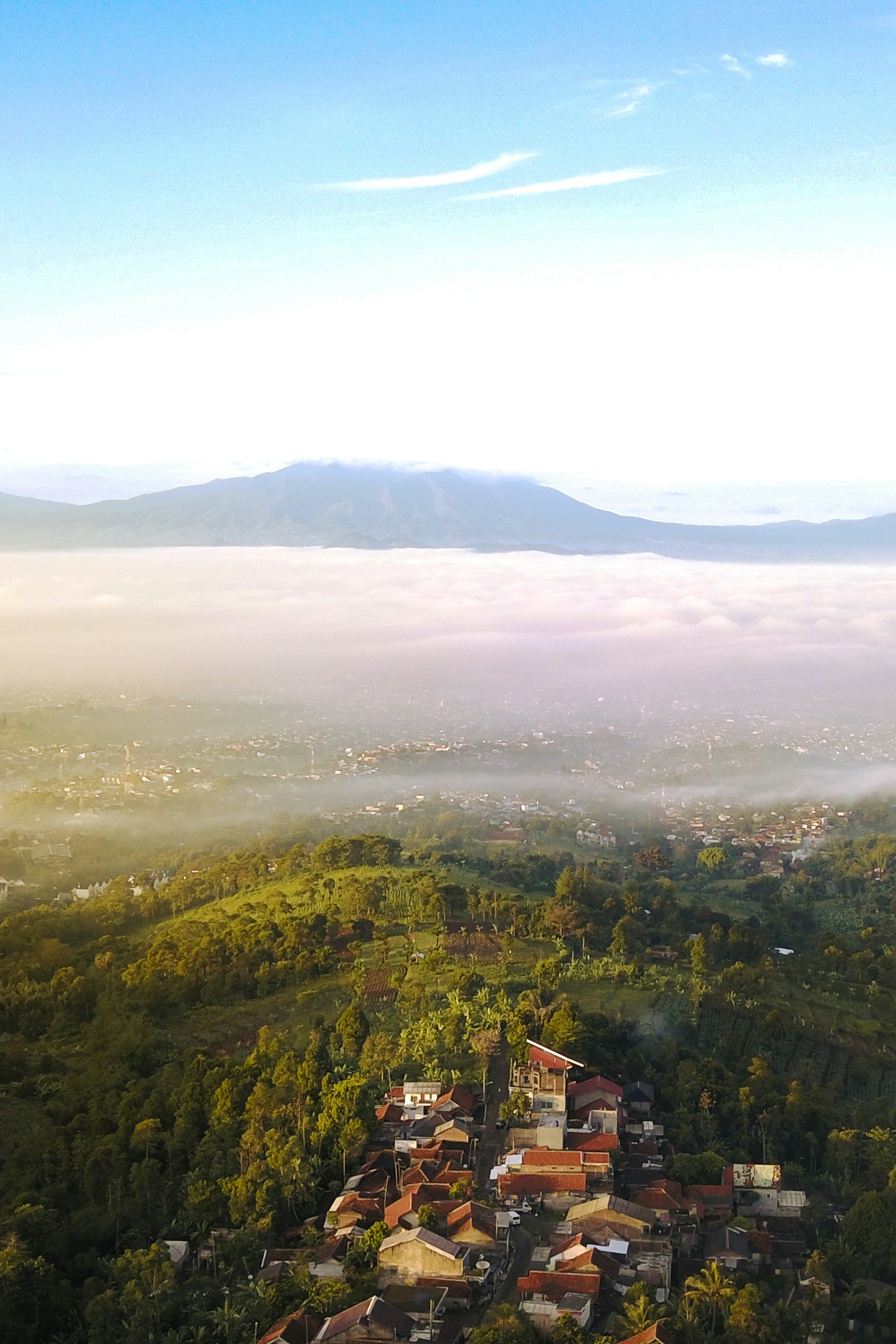 Scenic view of Nepal Van Java with misty mountains and traditional village houses in the foreground.
