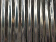 A close-up view of a corrugated metal sheet with vertical ridges and a reflective surface.