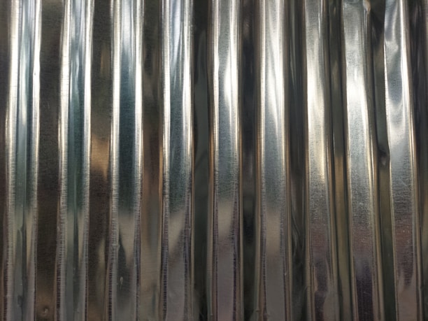 A close-up view of a corrugated metal sheet with vertical ridges and a reflective surface.