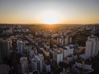 Aerial shot of a city skyline blending into green parks at sunset with warm golden tones.