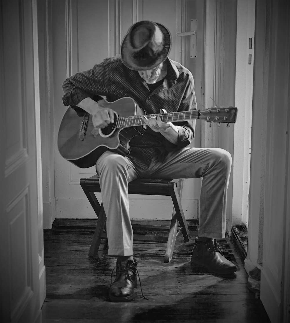 a man sitting on a stool playing a guitar