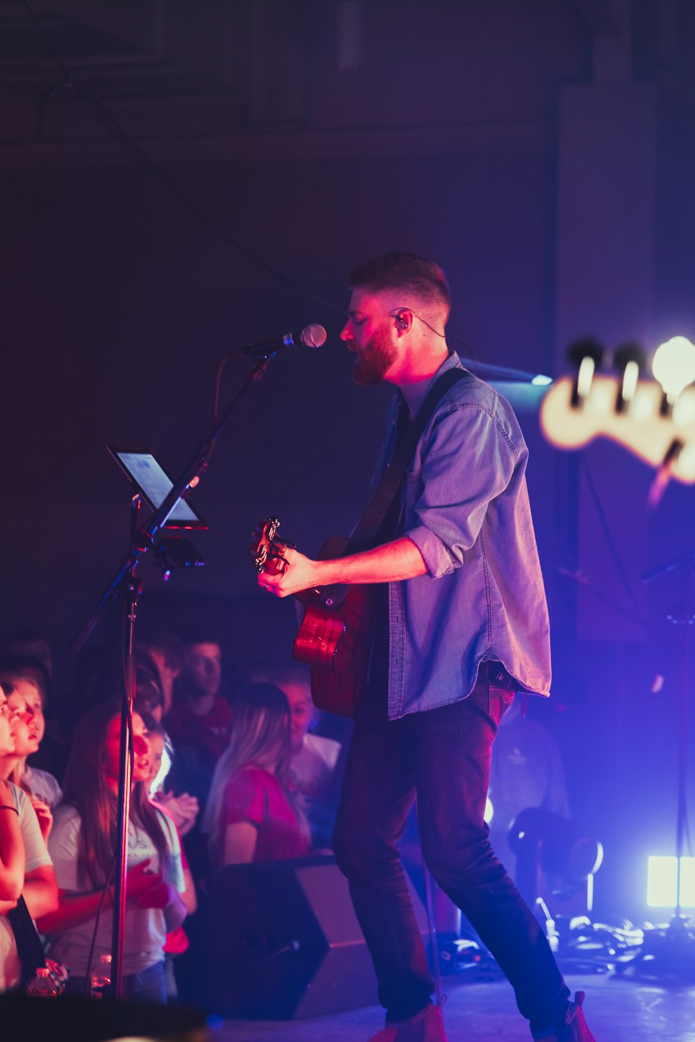 a man holding a microphone on a stage with a crowd watching