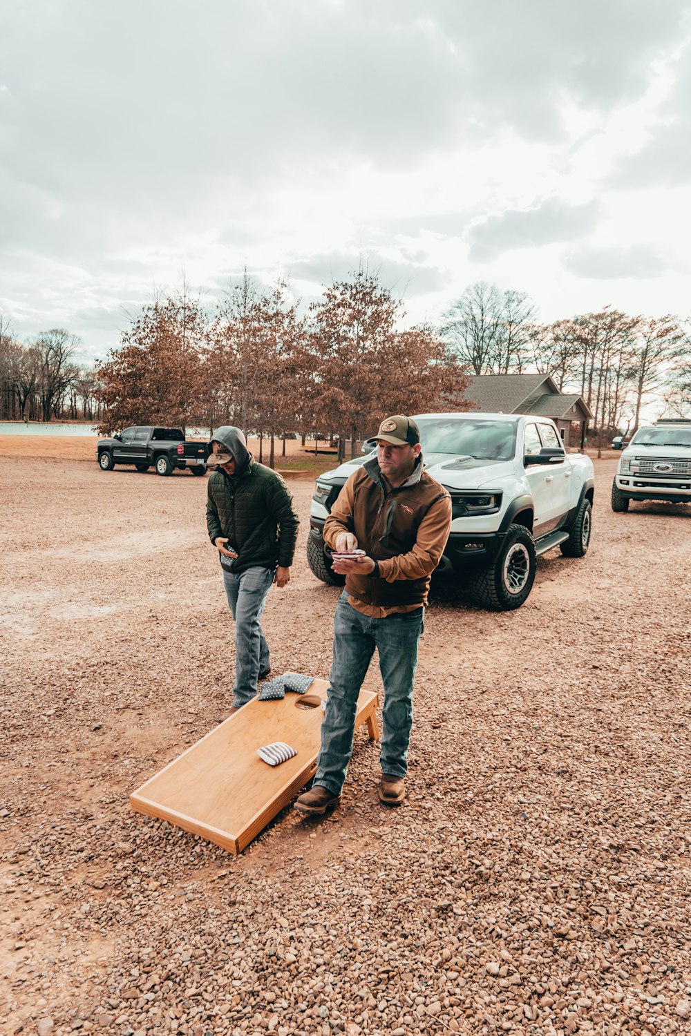 a couple of men standing on a wood board in a dirt field