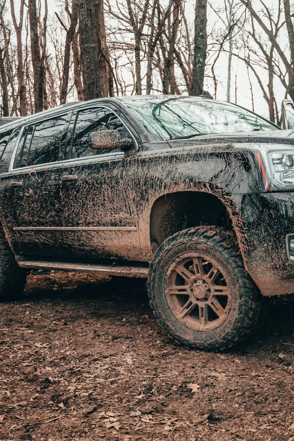 a car with a dent in the front parked in a forest